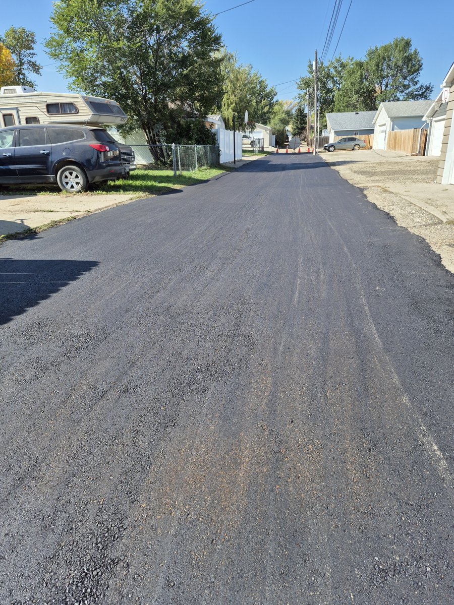 Fresh asphalt overlay being laid over an existing surface